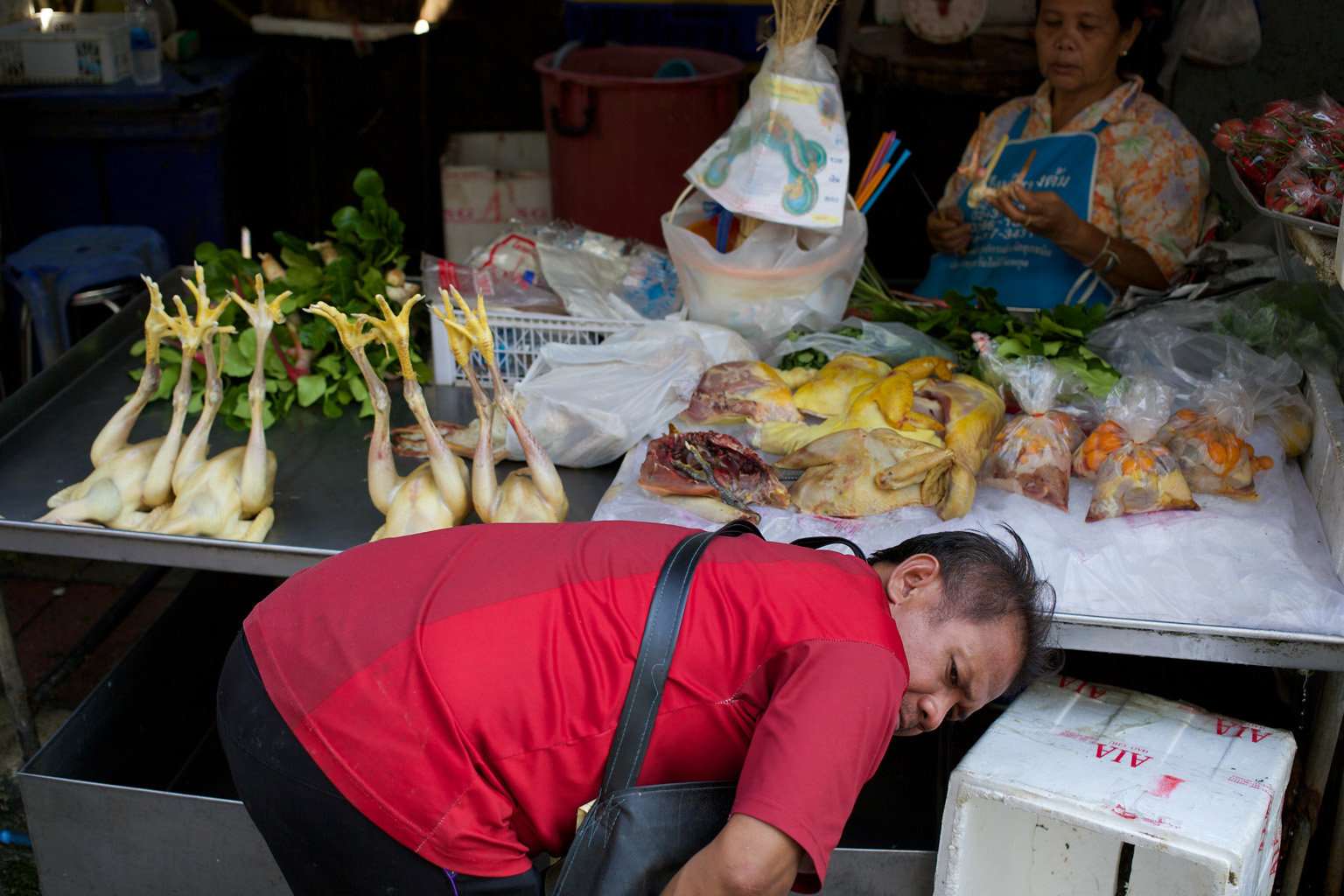 Customer bending to reveal chickens on a stall with legs in the air